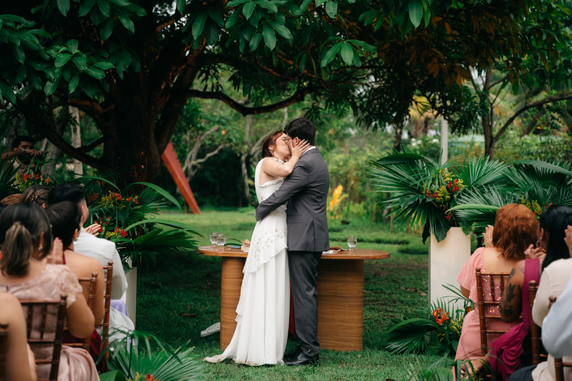Casal se beijando durante a cerimônia rodeado pelo jardim tropical
