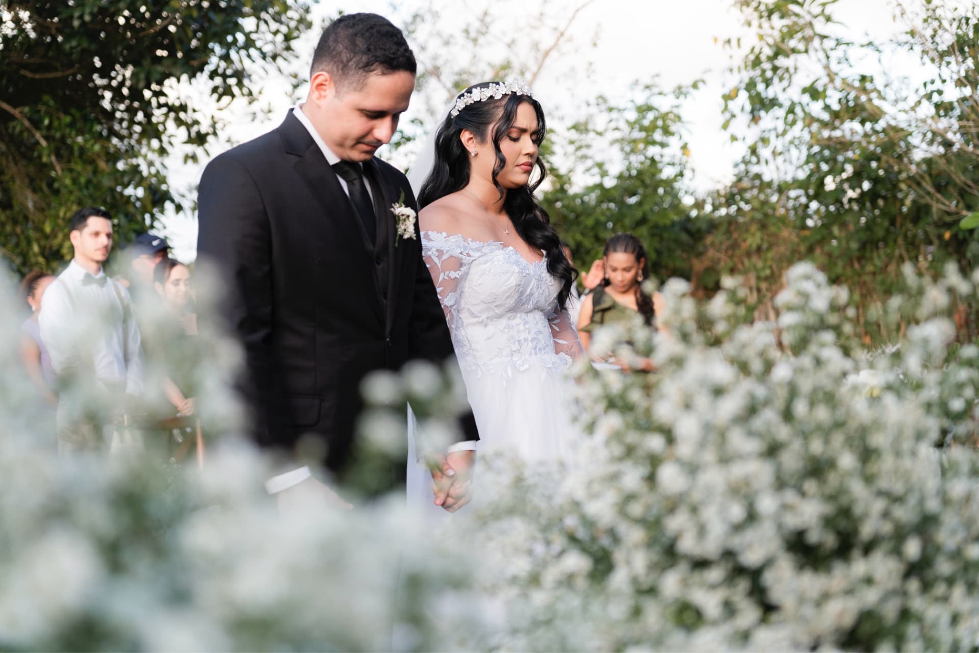 Noivos de mãos dadas entre arranjos de flores brancas na cerimônia